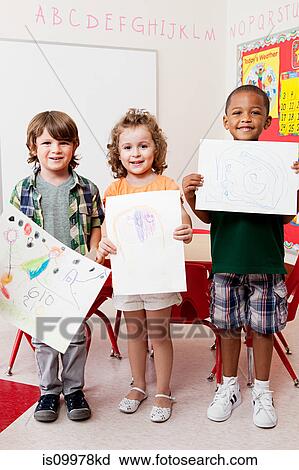 Stock Image - Three children holding pictures they have drawn. Fotosearch