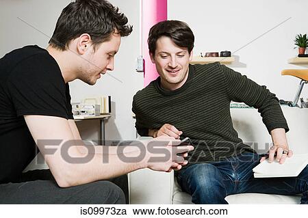 Stock Image - Two young casually dressed men sitting in office. Fotosearch