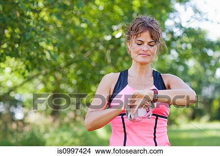 Woman checking watch during exercise View Large Photo Image Picture - Woman checking watch during exercise. Fotosearch