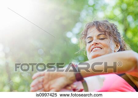Woman checking watch during exercise View Large Photo Image Stock Photography - Woman checking watch during exercise. Fotosearch