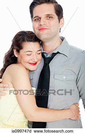 Stock Image - Young couple embracing against white background. Fotosearch