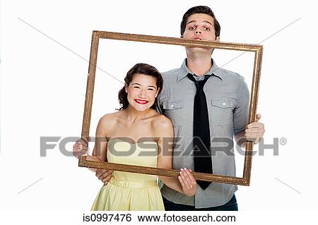 Young couple holding picture frame against white background View Large Photo Image Stock Photograph - Young couple holding picture frame against white background. Fotosearch