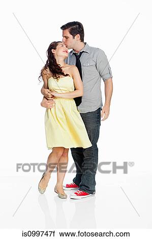 Stock Image - Young couple kissing against white background. Fotosearch