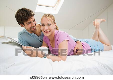 Young couple relaxing on bed View Large Photo Image Picture - Young couple relaxing on bed. Fotosearch