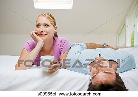 Young couple relaxing on bed View Large Photo Image Stock Image - Young couple relaxing on bed. Fotosearch