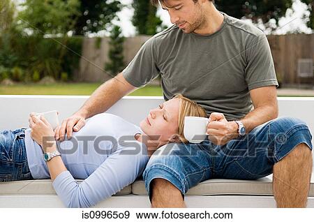 Young couple relaxing outdoors with coffee View Large Photo Image Stock Photo - Young couple relaxing outdoors with coffee. Fotosearch