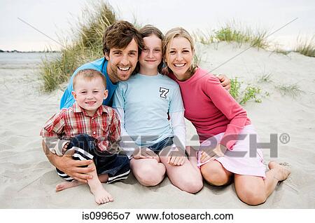 Stock Photo - Young family sitting on beach, portrait. Fotosearch