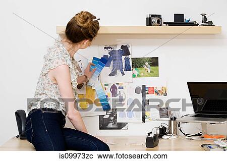 Stock Image - Young female fashion designer looking at color swatches. Fotosearch