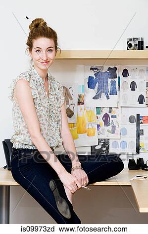 Young female fashion designer sitting on desk, portrait View Large Photo Image Stock Image - Young female fashion designer sitting on desk, portrait. Fotosearch