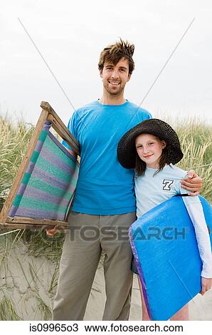 Stock Image - Young man at beach with daughter, portrait. Fotosearch
