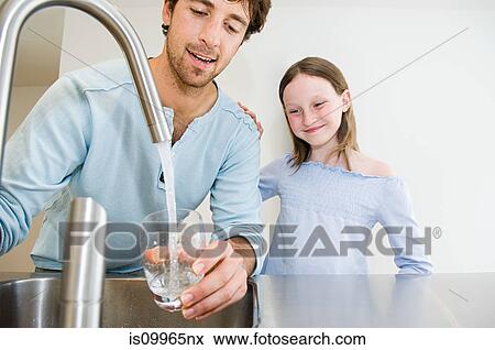 Young man filling glass of water for daughter View Large Photo Image Stock Photo - Young man filling glass of water for daughter. Fotosearch