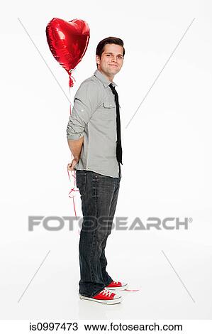 Young man holding balloon against white background View Large Photo Image Stock Image - Young man holding balloon against white background. Fotosearch