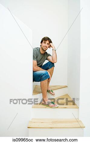 Young man sitting on staircase, portrait View Large Photo Image Stock Image - Young man sitting on staircase, portrait. Fotosearch