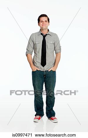 Young man with hands in pockets against white background View Large Photo Image Stock Image - Young man with hands in pockets against white background. Fotosearch