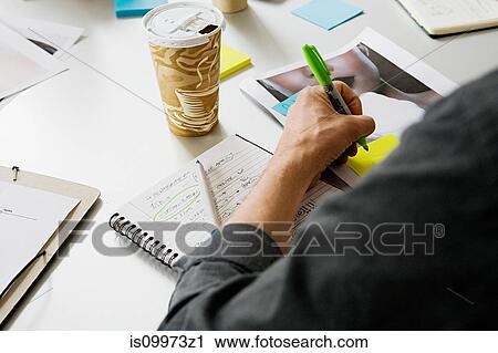 Stock Image - Young man writing on adhesive note. Fotosearch