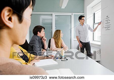 Young people sitting at conference table, man explaining chart View Large Photo Image Stock Image - Young people sitting at conference table, man explaining chart. Fotosearch