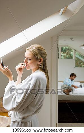 Picture - Young woman applying make up in bathroom. Fotosearch