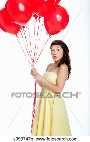 Stock Image - Young woman holding balloons against white background. Fotosearch
