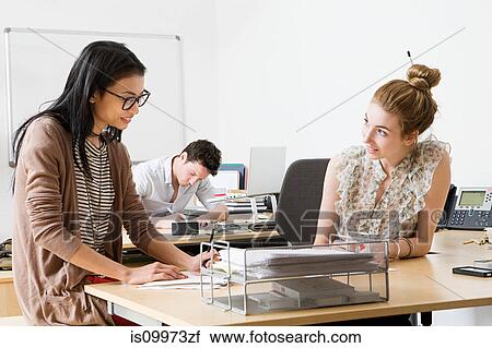 Young women in office, man working in background View Large Photo Image Stock Image - Young women in office, man working in background. Fotosearch