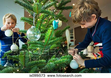 Boys decorating Christmas tree with baubles at home View Large Photo Image Stock Image - Boys decorating Christmas tree with baubles at home. Fotosearch