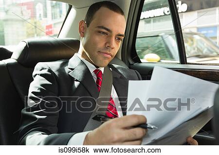 Stock Image - Businessman looking at papers in car. Fotosearch