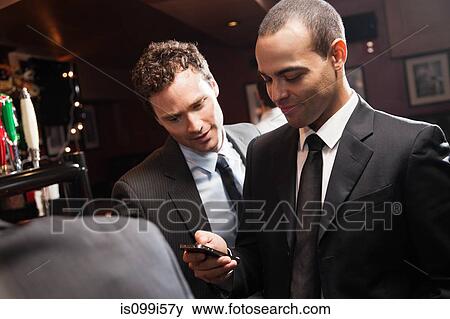 Businessmen looking at smartphone in bar View Large Photo Image Stock Photo - Businessmen looking at smartphone in bar. Fotosearch