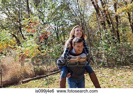Couple piggybacking outdoors View Large Photo Image Stock Photograph - Couple piggybacking outdoors. Fotosearch