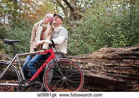 Couple sitting on log with bike View Large Photo Image Stock Image - Couple sitting on log with bike. Fotosearch