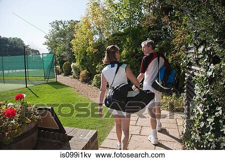 Stock Photo - Couple walking to tennis courts. Fotosearch