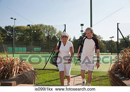 Stock Photo - Couple walking to tennis courts. Fotosearch