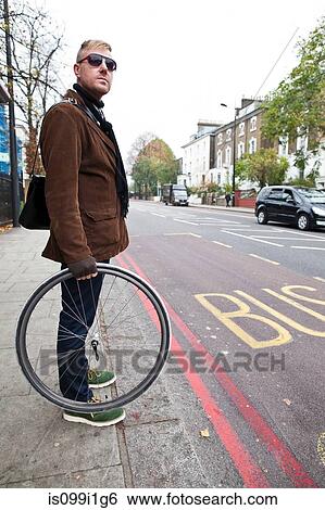 Cyclist holding bike wheel View Large Photo Image Stock Photograph - Cyclist holding bike wheel. Fotosearch