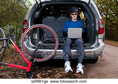 Cyclist using laptop from boot of car View Large Photo Image Stock Image - Cyclist using laptop from boot of car. Fotosearch