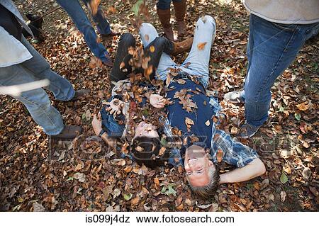 Friends throwing autumn leaves on couple View Large Photo Image Stock Photo - Friends throwing autumn leaves on couple. Fotosearch