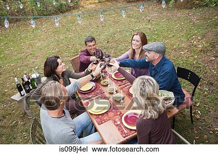 Stock Image - Friends toasting glasses at outdoor dinner. Fotosearch