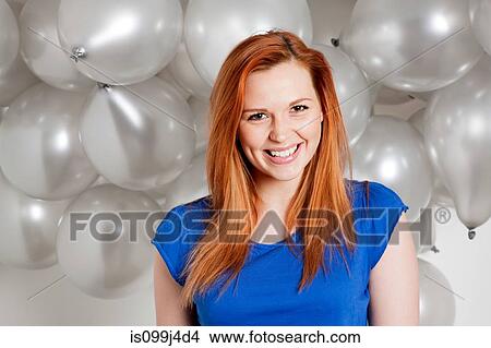 Picture - Happy young woman in front of balloons. Fotosearch