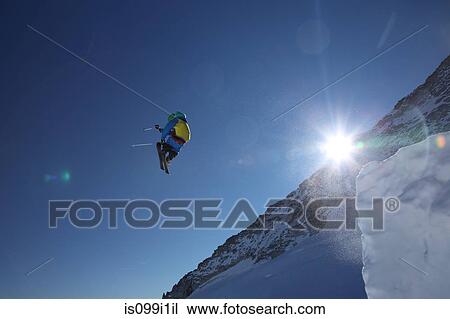 Stock Image - Male skier leaping against clear blue sky. Fotosearch