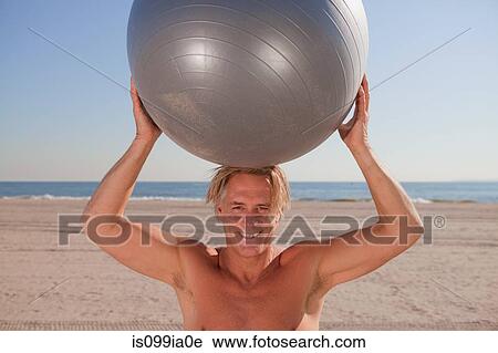 Man on beach holding exercise ball View Large Photo Image Stock Image - Man on beach holding exercise ball. Fotosearch