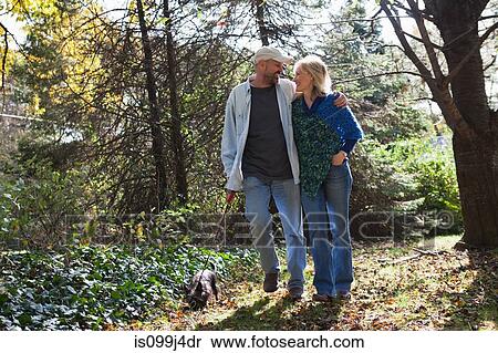 Stock Photography - Mature couple walking dog. Fotosearch