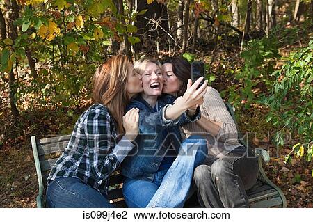 Stock Image - Mature female friends photographing themselves. Fotosearch