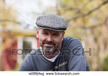 Stock Image - Mature man in flat cap outdoors. Fotosearch