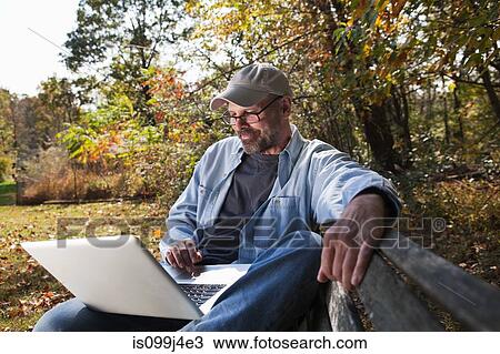 Mature man using laptop outdoors View Large Photo Image Stock Image - Mature man using laptop outdoors. Fotosearch