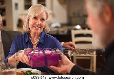 Stock Photo - Mature woman at dinner party receiving gift. Fotosearch