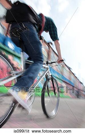 Mid adult cyclist riding bike across bridge View Large Photo Image Stock Photograph - Mid adult cyclist riding bike across bridge. Fotosearch