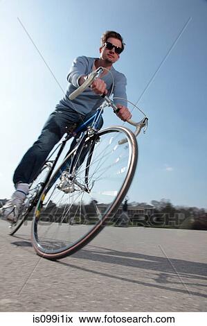 Stock Photo - Mid adult cyclist riding bike. Fotosearch