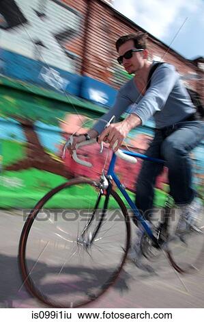 Mid adult cyclist riding passed graffiti View Large Photo Image Stock Photograph - Mid adult cyclist riding passed graffiti. Fotosearch