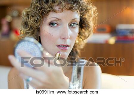 Mid adult woman applying lipstick View Large Photo Image Picture - Mid adult woman applying lipstick. Fotosearch