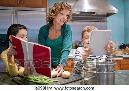 Mid adult woman cooking in kitchen with sons View Large Photo Image Stock Photo - Mid adult woman cooking in kitchen with sons. Fotosearch