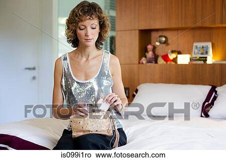Picture - Mid adult woman putting compact into purse. Fotosearch