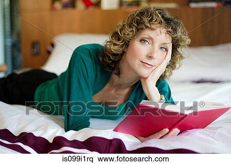 Mid adult woman reading book in bedroom View Large Photo Image Stock Photography - Mid adult woman reading book in bedroom. Fotosearch