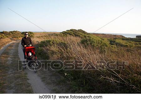 Stock Photograph - Mother pushing stroller along country path. Fotosearch